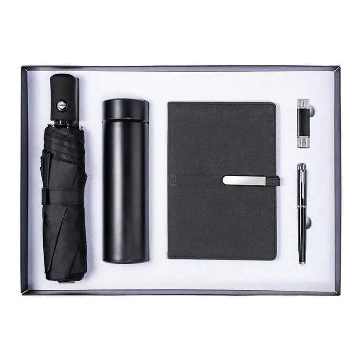 an open box containing a black umbrella, pen and notepad with the contents in it