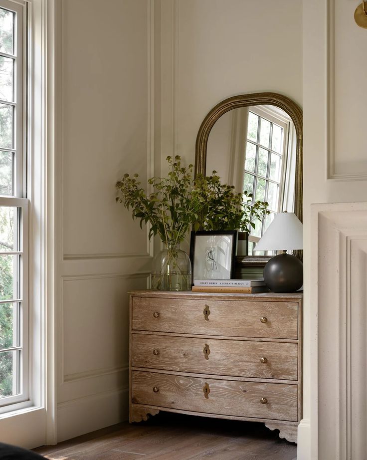 a dresser with a mirror and flowers on it