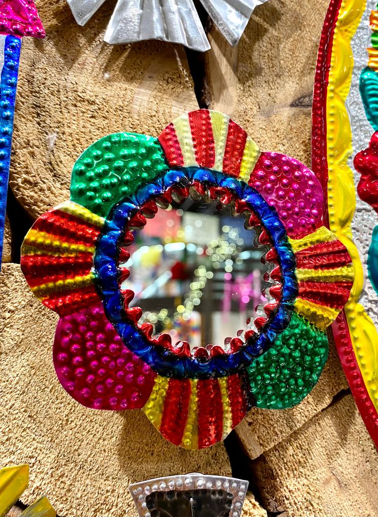 a colorful flower shaped mirror hanging on the side of a wall next to other decorations