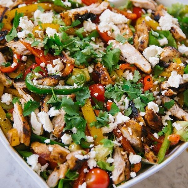 a white bowl filled with chicken and veggies on top of a marble table