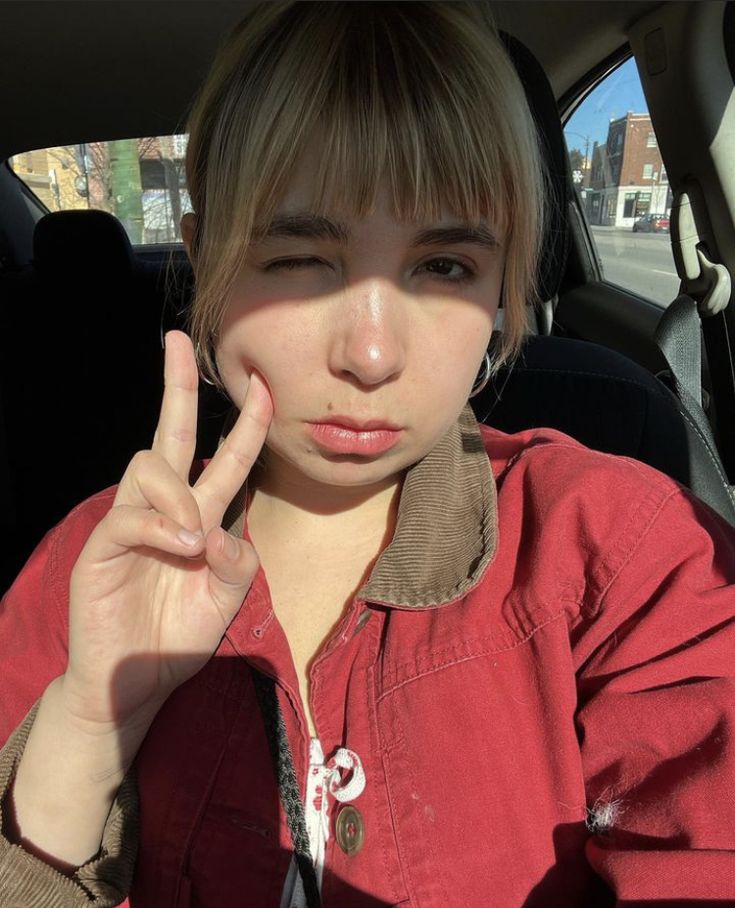 a woman sitting in the back seat of a car making a peace sign with her hand