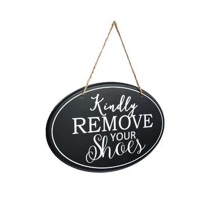 a black and white sign that says,'kindly remove your shoes'hanging from a rope