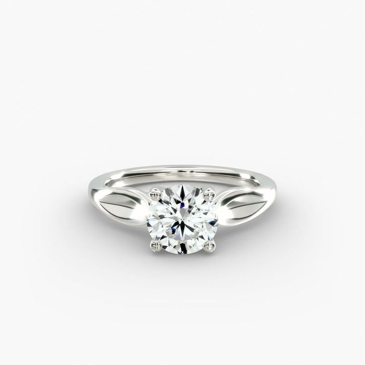 a white gold engagement ring with a round brilliant cut diamond in the center, on a plain surface