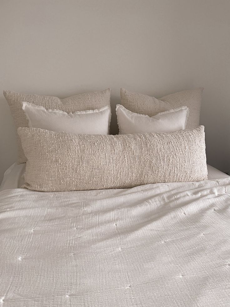 a white bed with two pillows on top of it