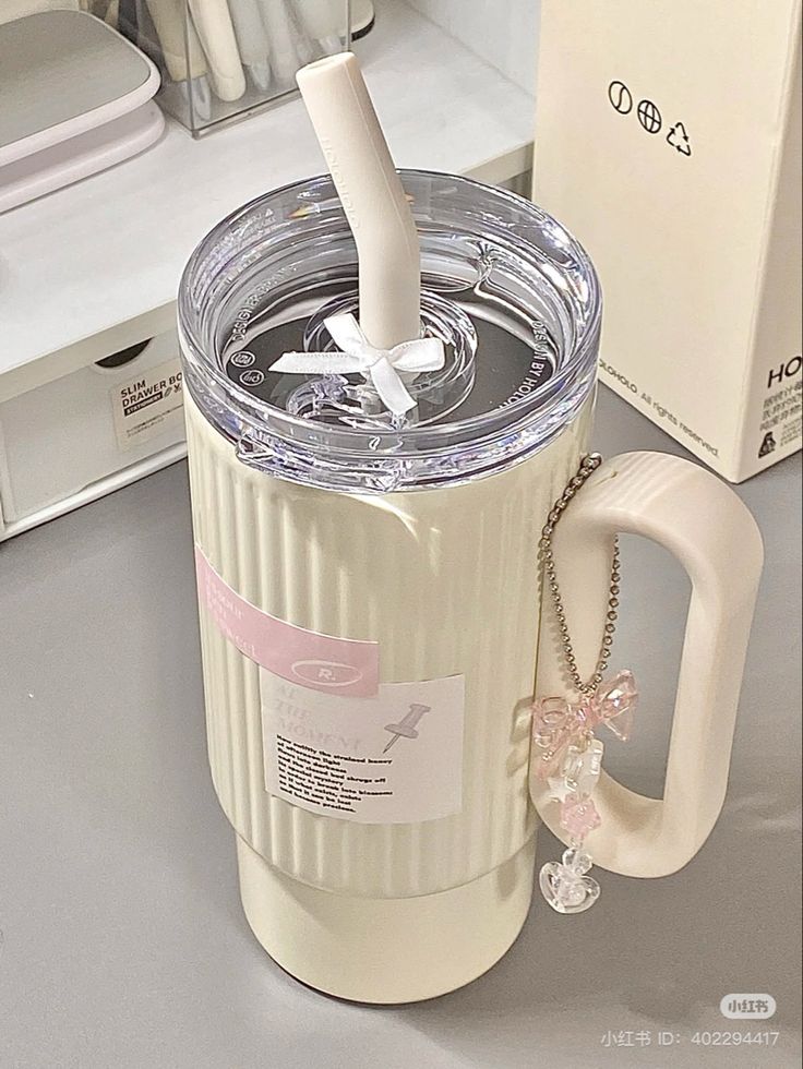 a white cup with a straw sticking out of it sitting next to a box and keychain