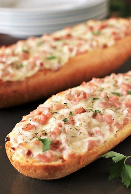 two pieces of bread with cheese and parsley on top, sitting on a table