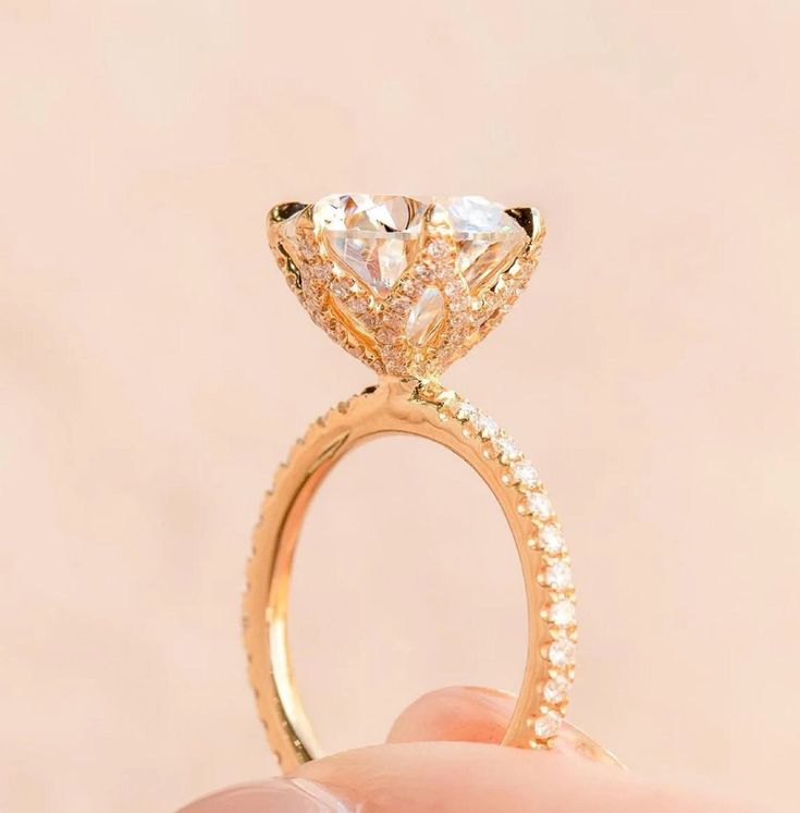 a hand holding an engagement ring with a pear shaped diamond on it's side