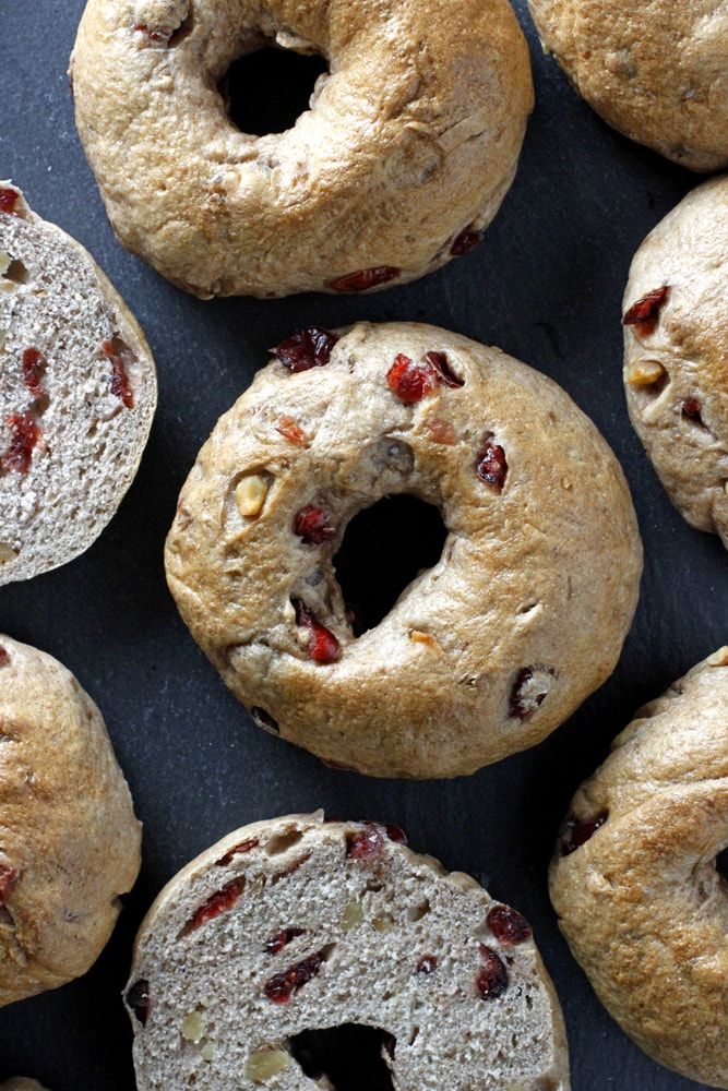 freshly made bagels with cranberry toppings on a black surface, ready to be eaten