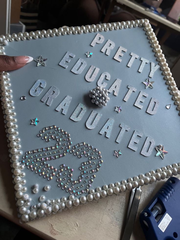 a cake that has been decorated with pearls and beads on it's side, in the shape of a graduation cap