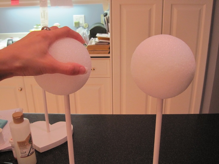 a person holding two lollipops on top of each other in front of a counter