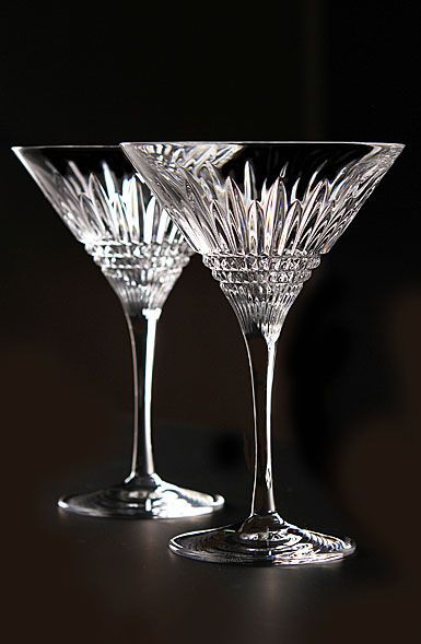 two wine glasses sitting next to each other on a counter top in front of a black background