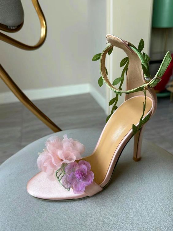 Step into a garden of elegance with the Claire Floral Heels. These stunning heels feature a delicate pink base adorned with intricate floral details, making them the perfect accessory for a romantic and feminine look. The ankle strap is beautifully decorated with green leaf accents, adding a whimsical touch that complements the soft, ethereal flowers on the toe. Crafted with a satin finish, the Claire Floral Heels offer a luxurious feel and a comfortable fit. The open-toe design showcases your p Pink Wedding Heels, Ethereal Flowers, Stunning Heels, Pink Wedding Shoes, Formal Accessories, Pink High Heels, Floral Heels, Floral Sandals, Heels Outfits