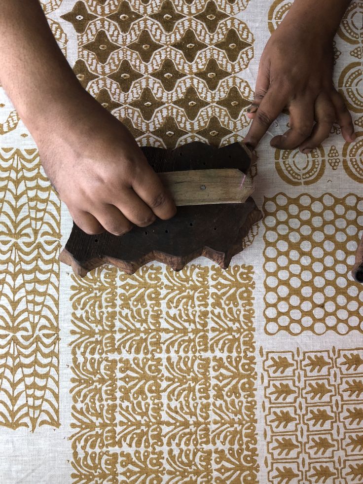 a person is using a piece of wood to cut up something on a tablecloth