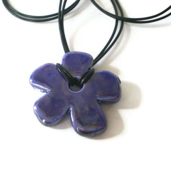 a purple flower pendant on a black cord