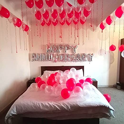 a bedroom decorated with balloons and streamers for an anniveristry party on valentine's day