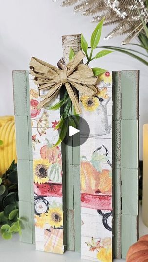 a wooden block with a bow and sunflowers on it sitting next to some pumpkins