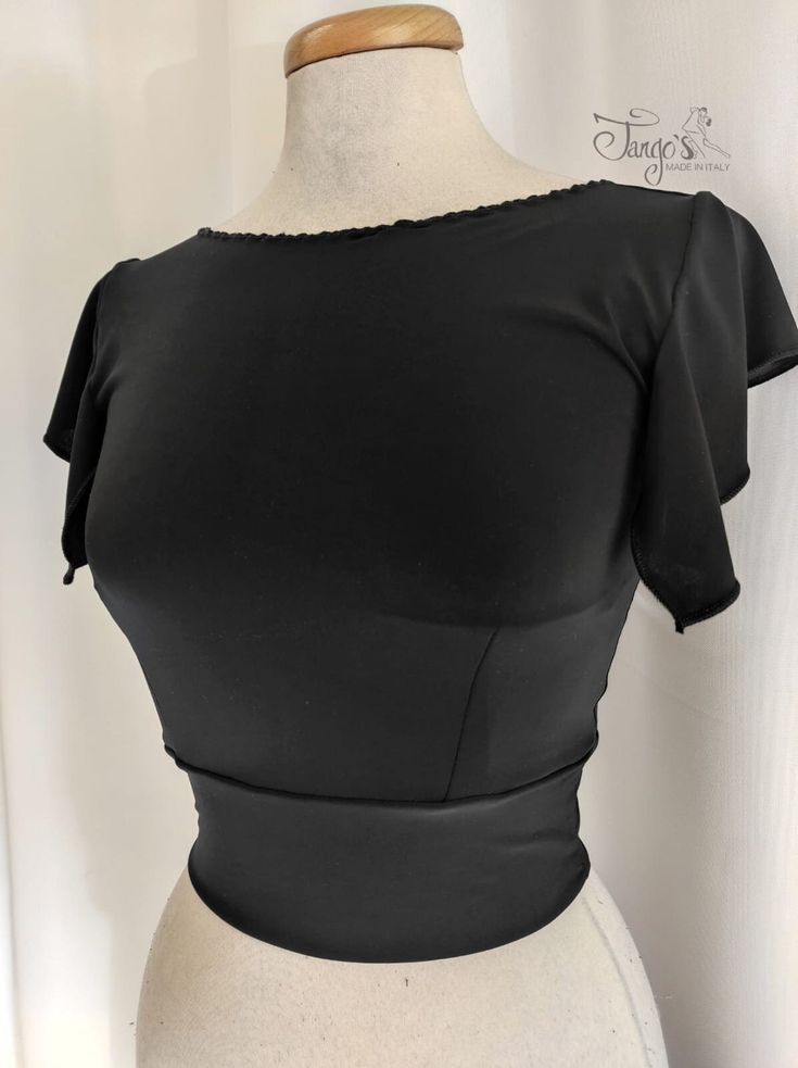 "Short top made of stretch sweater, deep neckline on the back and short sleeves with ruffles. Contact us for information. www.tango-s.com - info [!at] tango-s.com TANGO'S offers you exclusive and original models, garments of a refined and unique elegance, sartorial workmanship with attention to every detail, made in a rigorous \"Made in Italy\" combining Quality, Passion, Elegance and Comfort. Estimated delivery time 10 days Express shipping 1-2 days." Elegant Fitted Tops With Cap Sleeves, Fitted Flutter Sleeve Top For Parties, Fitted Flutter Sleeve Top For Night Out, Chic Fitted Tops With Flutter Sleeves, Chic Fitted Tops With Cap Sleeve, Fitted Black Dancewear Top, Elegant Fitted Tops With Flutter Sleeves, Chic Fitted Cap Sleeve Tops, Summer Evening Tops With Fitted Bodice