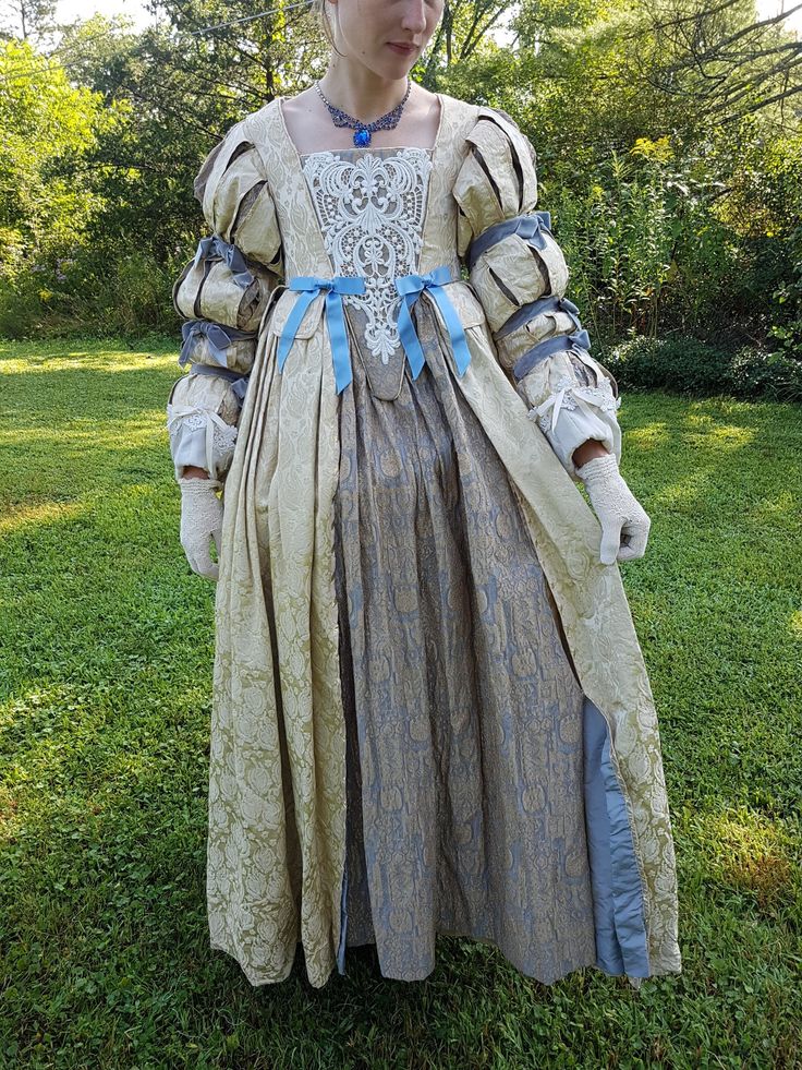 Elizabethan Renaissance dress with beautiful period-looking beige-gold pattern. Best choice for period balls and dancing, Renaissance fairs, Venezian Carnival, Wedding, Masquerade, Faire and other events. Made with beautiful brocade (skirt) and gold Damascus (gown) The dress consists of the gown and skirt sewn together in one piece, the skirt is fully lined. check out pictures of the inside of the bodice  The bodice front is accented with lace and blue ribbons.  The bodice is boned. It laces through sturdy brass grommets The sleeves have lace on the bottom part. and they have velvet ribbons W 30-32 circumference This dress was created for the Shakespeare theater play The 3 Musketeers (see pictures). Jewelry, gloves, and handbag included. shipping is not included dress weights 6lbs Historical Baroque Gown For Costume Use, Baroque Gown With Historical Design For Costume, Regency Style Gold Dress With Historical Design, Regency Style Wedding Dresses For Medieval Festivals, Victorian Baroque Medieval Wedding Dress, Victorian Gown With Historical Design For Fancy Dress, Medieval Baroque Dress For Weddings, Ceremonial Regency Dress With Historical Design, Regency Style Historical Ceremonial Dress