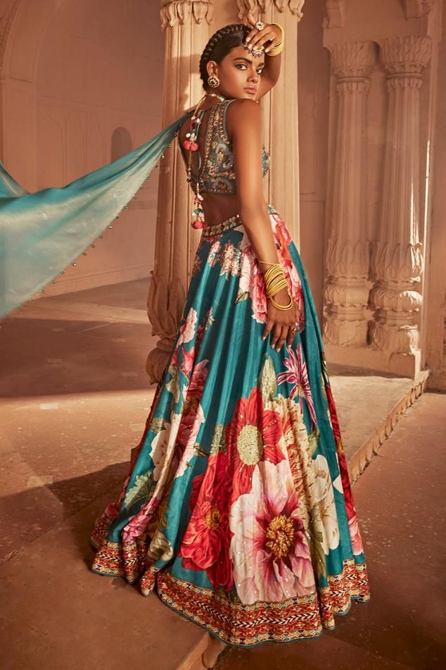 Teal blue attached cancan lehenga with multi coloured floral motifs and intricate hand embroidery. Comes with padded, embroidered blouse with intricate thread and hand beadwork on the yoke and a co-ordinated dupatta.
Components: 3
Type Of Work: Floral
Neckline: Leaf
Sleeve Type: Sleeveless
Fabric: Lehenga and Blouse: Raw Silk, Dupatta: Georgette
Color: Blue
Other Details: 
Back tassel tie-up
Length:
Blouse: 14 inches
Lehenga: 44 inches
Model height: 5ft 8inches, wearing size S
Note: All the jewe