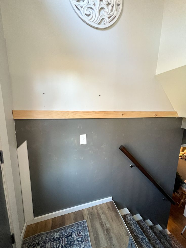 an empty room with stairs leading up to the ceiling and a clock on the wall