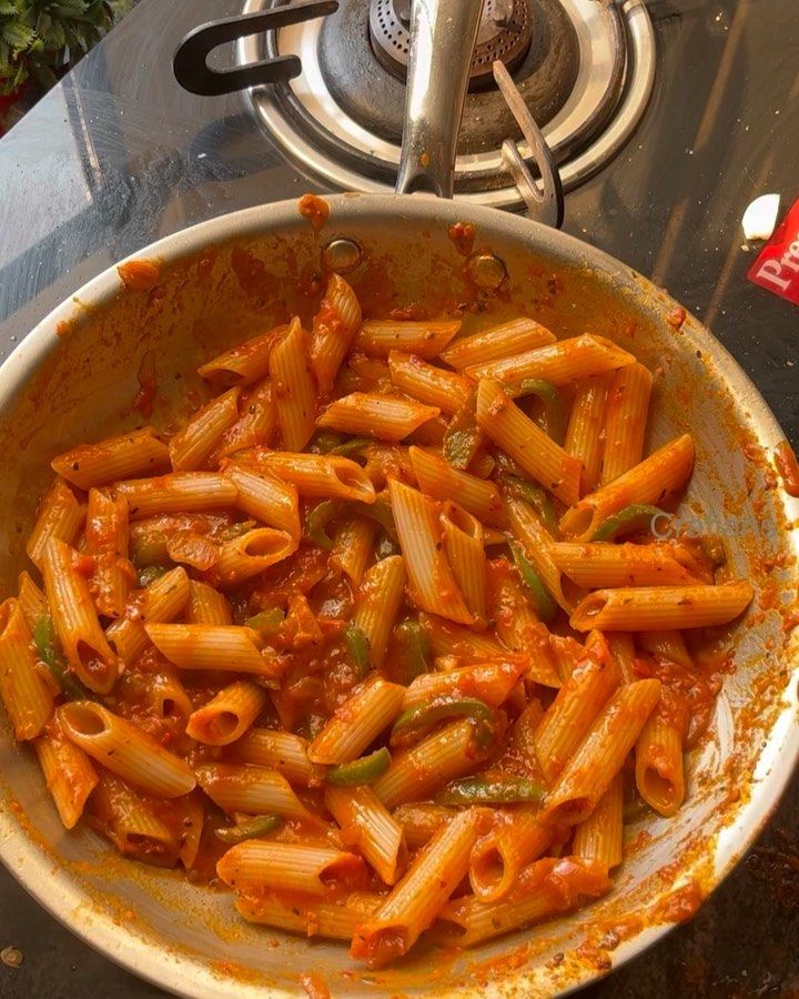 a pan filled with pasta and sauce sitting on top of a stove next to a burner