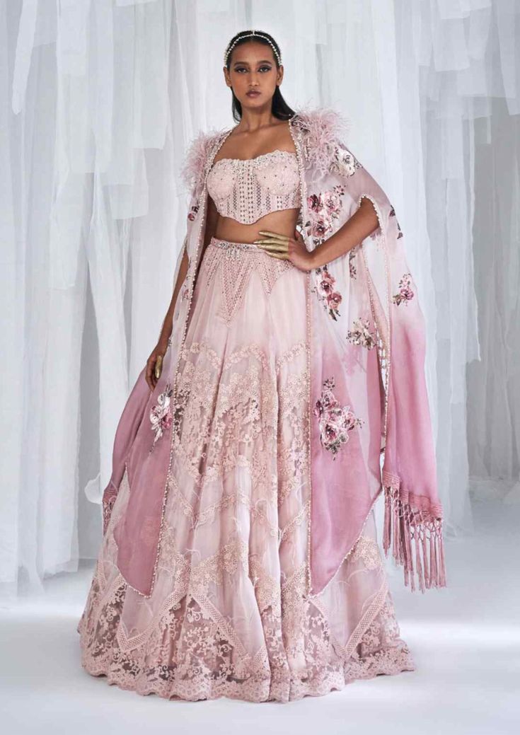 Editor's Note Featuring a chantilly organza lehenga with a chantilly corset with pearl work and an organza cape embellished with feathers and a leather belt. Fabric: Organza Color: Pink Components: Lehenga, corset, belt, cape Occasion: Wedding Care: Dry Clean Only Customize Your Outfit Can't find the size you're looking for? No stress. Just select the size "Custom" while adding the item to your cart. We will follow up with you for your body measurements. To request a color or design customizatio Corset Lehenga, Lehenga Cape, Dolly J, Organza Cape, Jacket Lehenga, Cape Lehenga, Cape Set, Organza Lehenga, Pearl Work