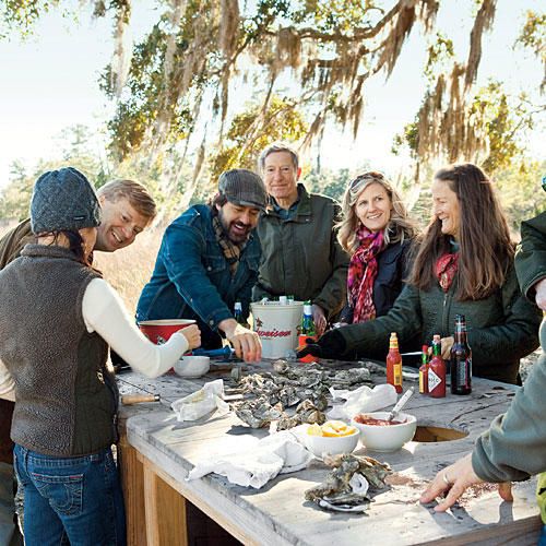 a group of people standing around a table with food on it