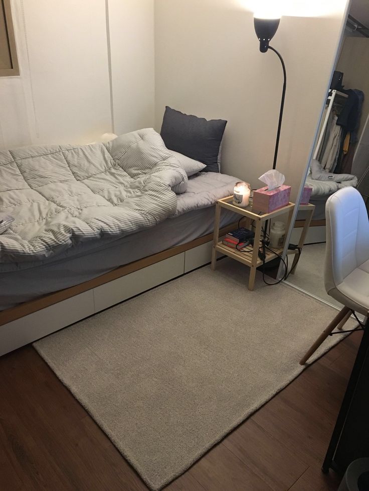 a small bedroom with a bed, desk and chair next to a mirror on the wall