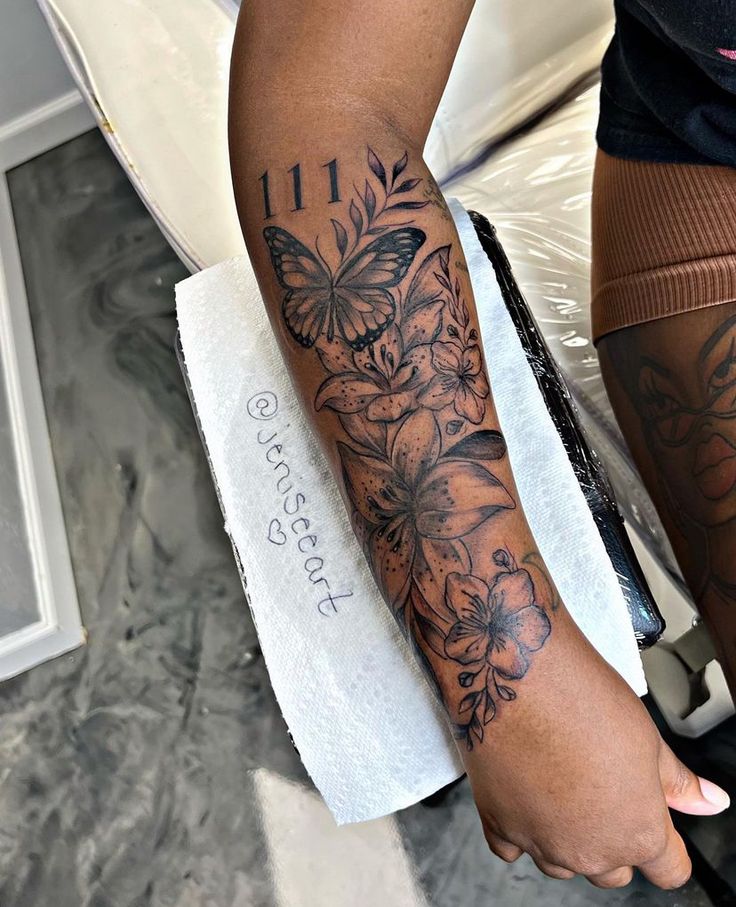 a woman's arm with flowers and butterflies tattooed on her left arm, next to a toilet