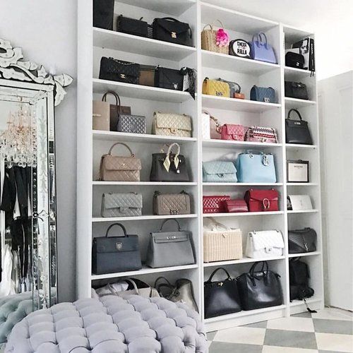 a room filled with lots of purses and handbags on shelves next to a mirror