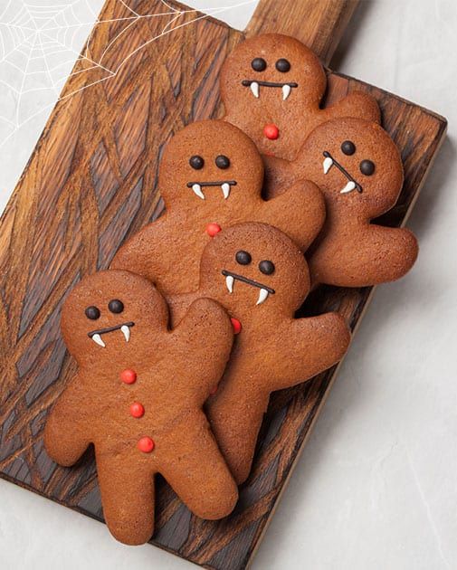 some very cute looking cookies that are on a wooden board with eyes and teeth in the shape of men