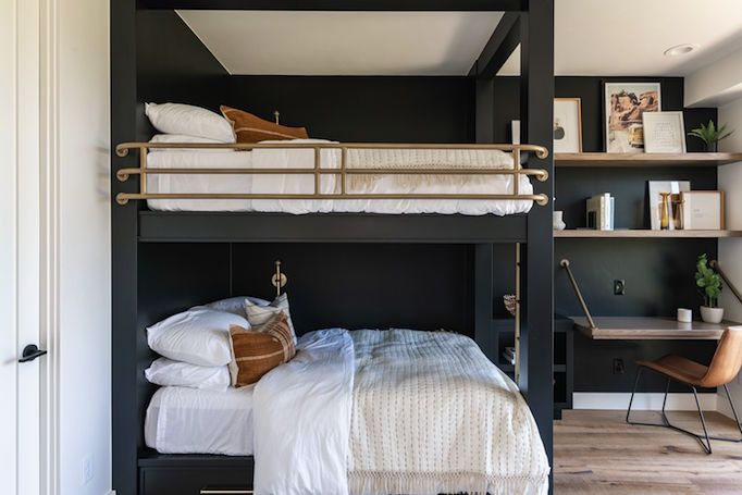 a bunk bed sitting in the middle of a bedroom next to a desk and chair