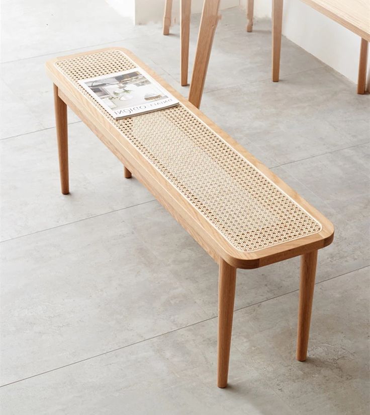 a wooden bench sitting on top of a cement floor next to two tables with magazine holders