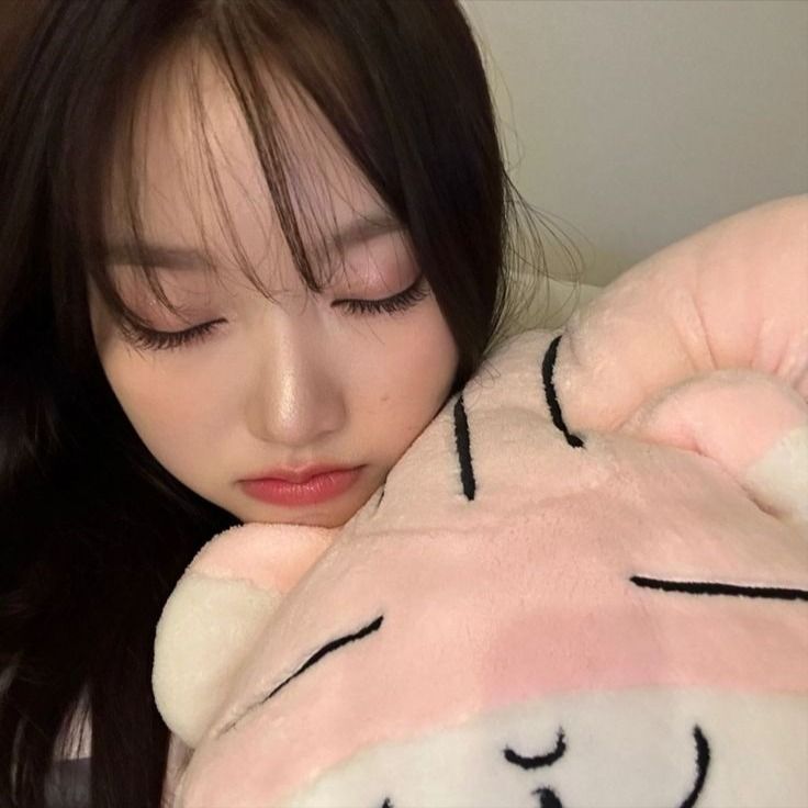 a woman is hugging a stuffed animal with her eyes closed