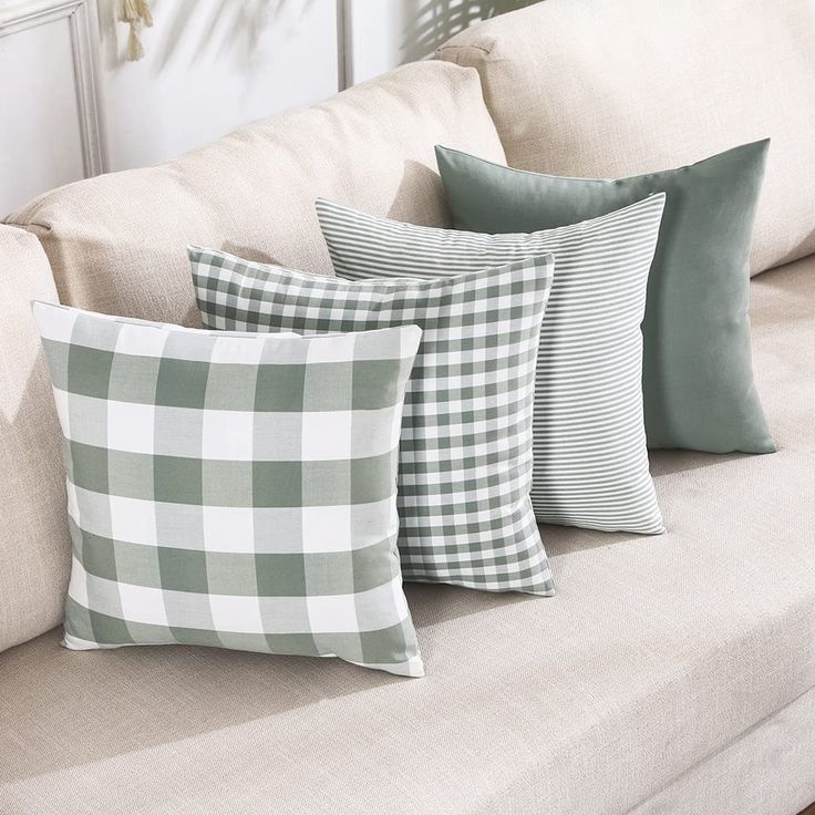 four green and white pillows sitting on top of a couch