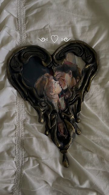 a heart shaped photo frame with two people in it on top of a white sheet