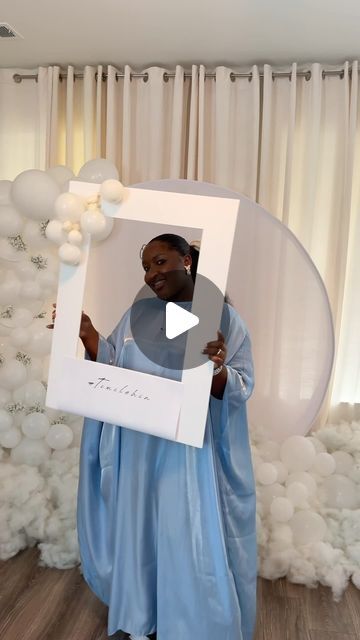 a woman in blue dress holding up a white frame with balloons behind her and the words thank you written on it