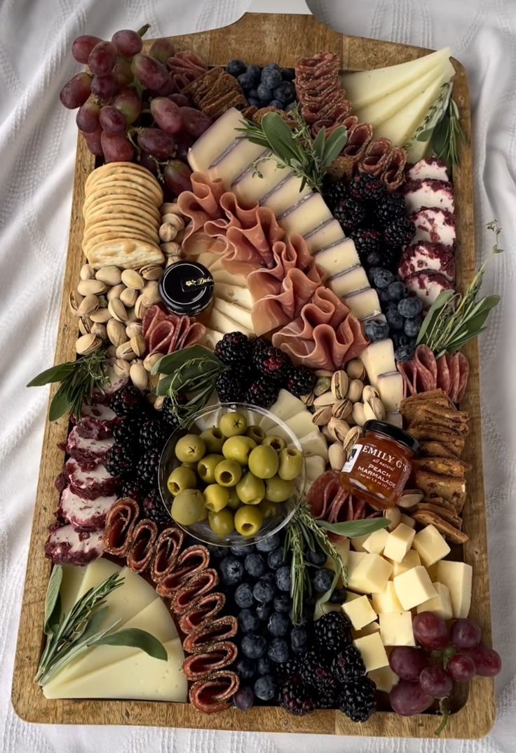 a wooden platter filled with cheese, olives and other foods