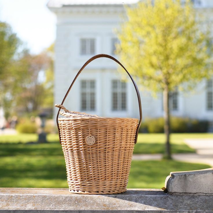 a wicker basket sitting on top of a stone wall in front of a white house