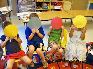 four children sitting in chairs with paper hats on their heads