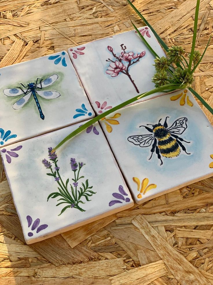 four tiles with different designs on them sitting on top of the floor next to grass