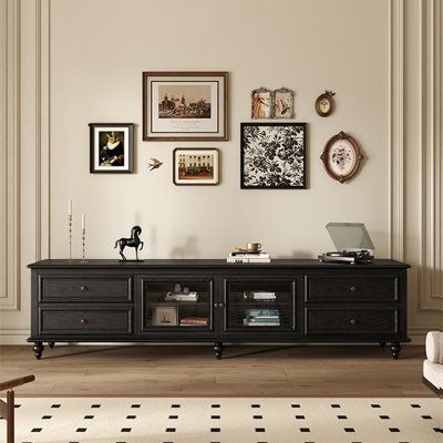 a living room with pictures on the wall and a black tv stand in front of it