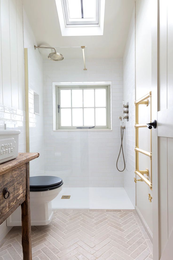 a bathroom with a toilet, sink and skylight in the window above it is white tile flooring