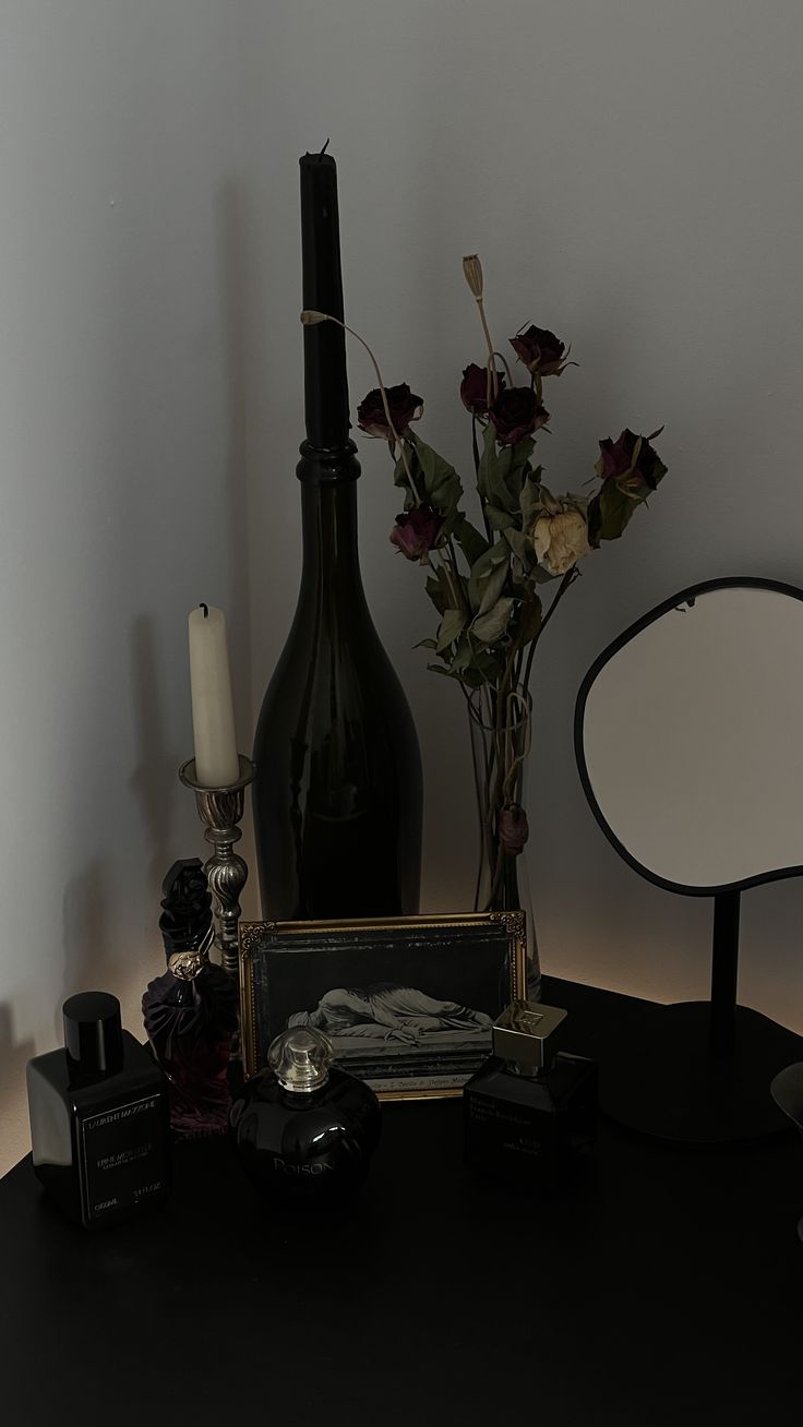 a black table topped with a vase filled with flowers next to a mirror and lamp