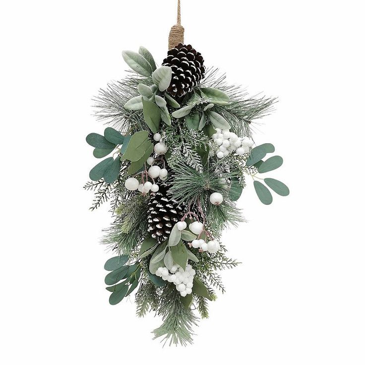 a christmas wreath with pine cones and greenery hanging from a rope on a white background