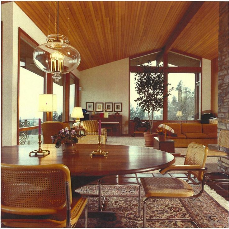 a dining room table and chairs in front of large windows with wood paneling on the ceiling