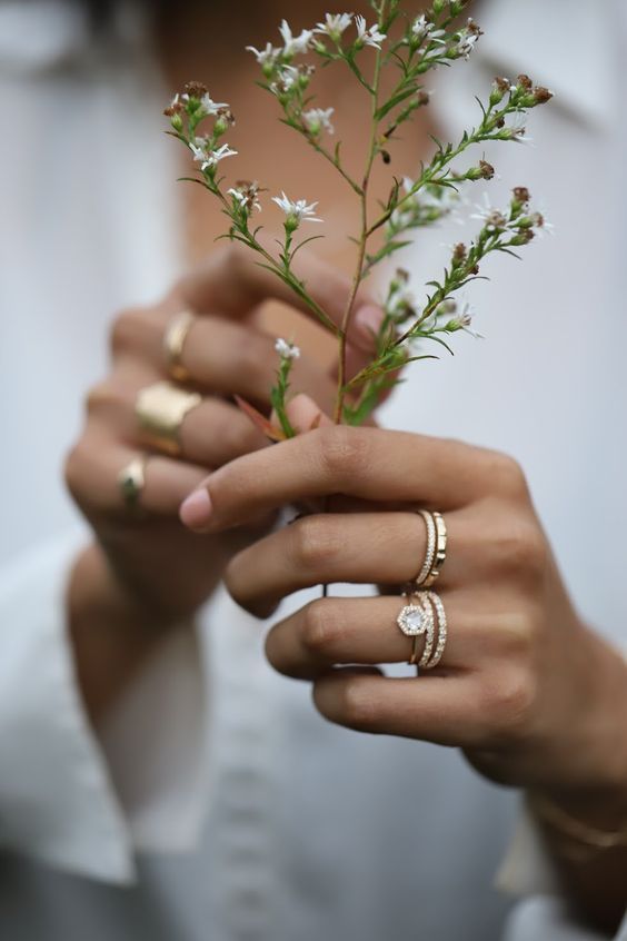 a woman holding flowers with two rings on her fingers