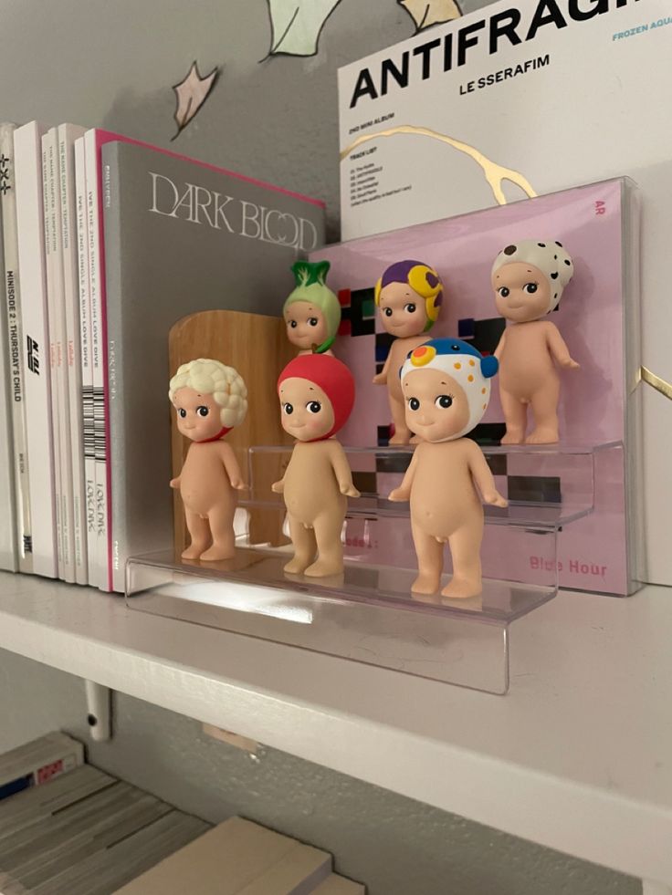 some little dolls are sitting on a shelf