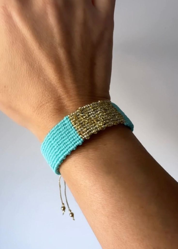 a woman's arm wearing a bracelet with gold and blue beads on it,