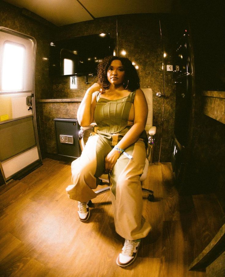 a woman sitting on top of a chair in a room with wooden floors and walls